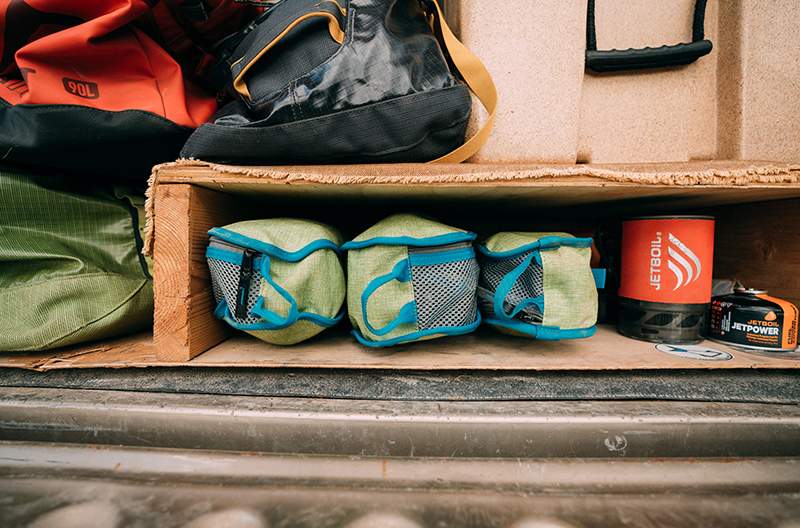 Camping gear neatly stowed in the back of a truck with a bed cap.