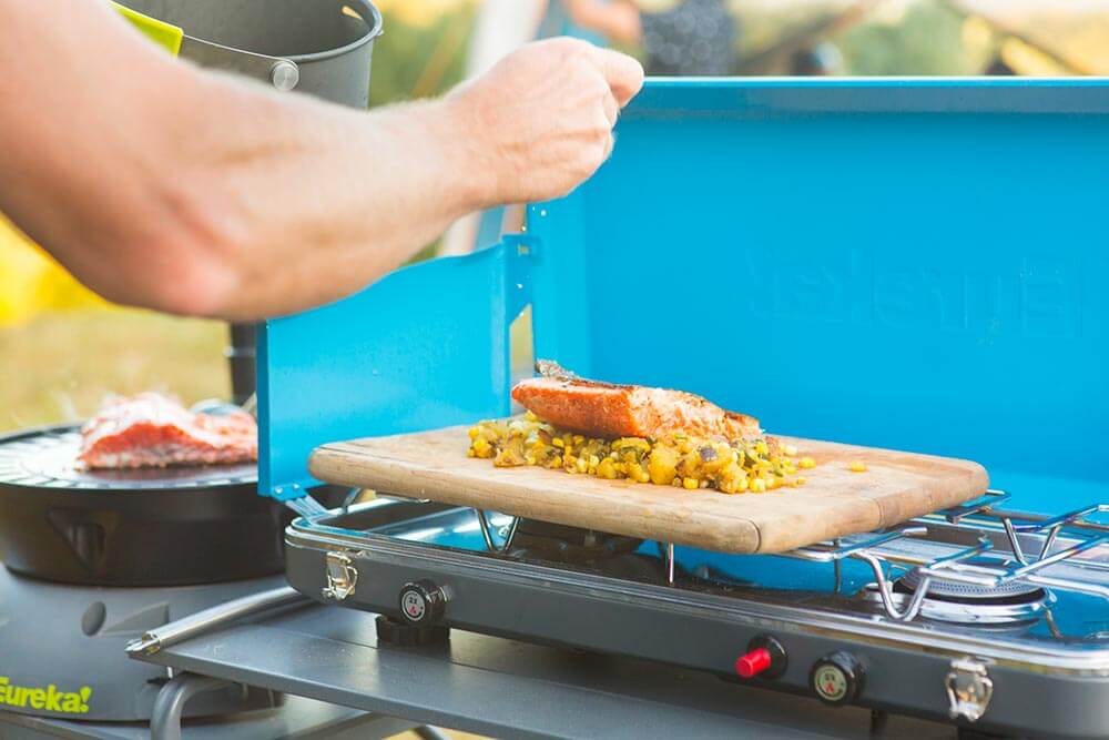 Sprinkling salt onto a salmon and lemon dish cooked on the Eureka! Ignite camp stove