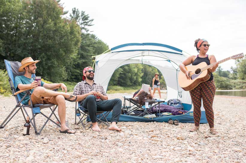 Campers enjoying Eureka! chairs, cot and tent by the river