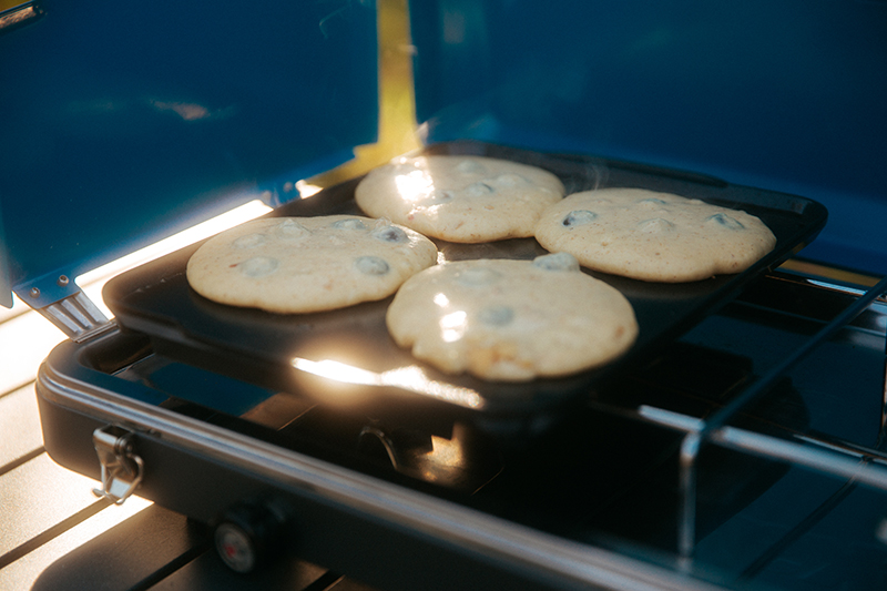 Four pancakes cooking on a griddle on a Eureka camp stove. 