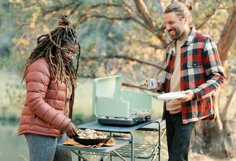 Couple enjoying a camp carne asada nachos meal cooked in an iron skillet on the Eureka! Ignite camp stove