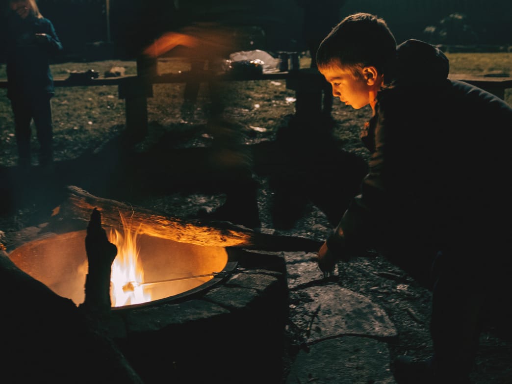 Boy by campfire at night