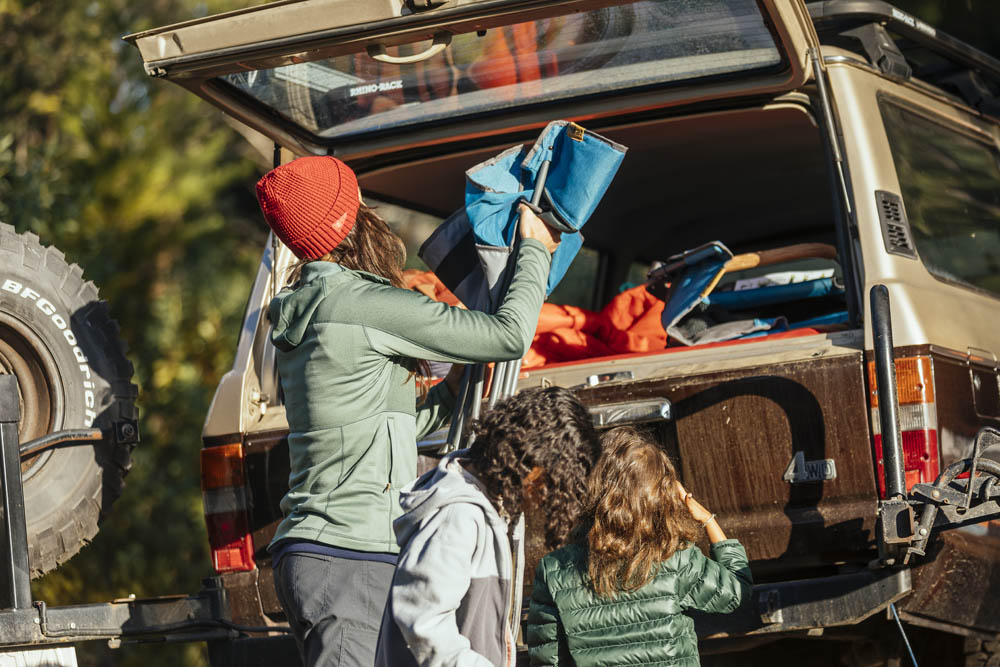 Woman loading Eureka camp chair into back of station wagon for camping trip
