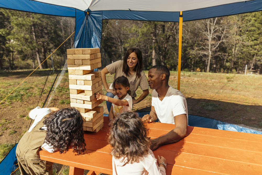 Family under the Eureka Northern Breeze Shelter playing Jenga tower game