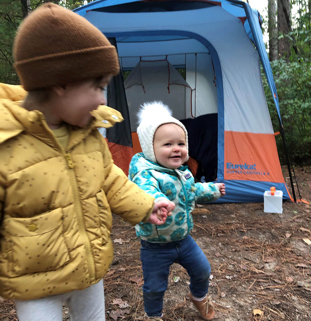 Two kids bundled up at camp site standing in front of the Eureka! Copper Canyon XL 4 Tent