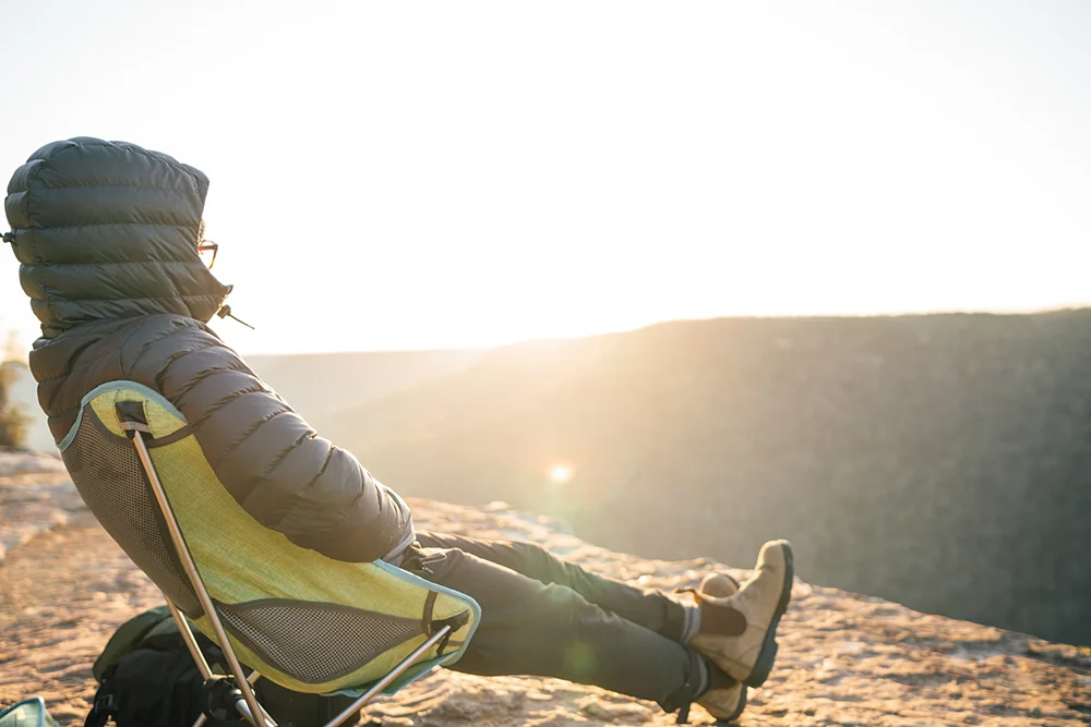 Caziah Franklin sits in a camp chair and looks out over a scenic vista at sunset. 