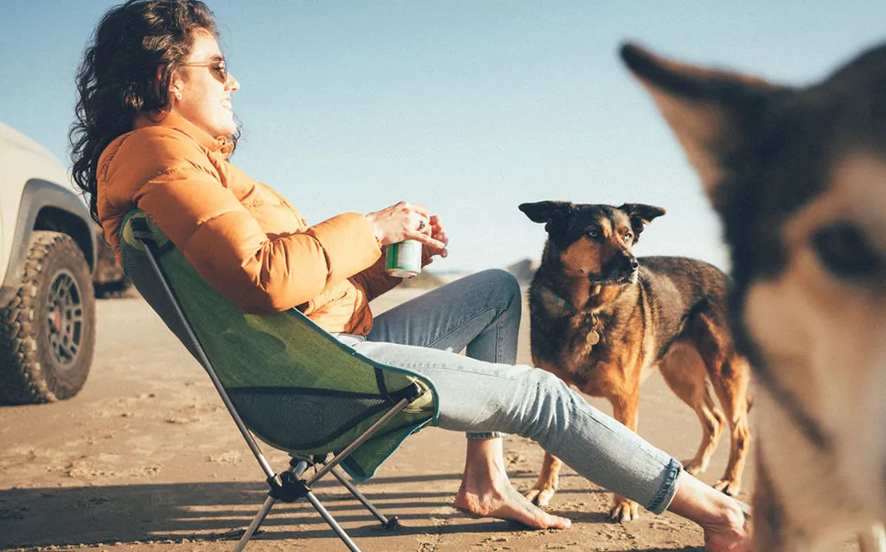 Kelsey Kagan sits in a Eureka Tagalong Lite camp chair in the desert with her two dogs. 