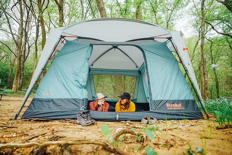 Two young women laying in a Kohana tent looking out through the open door.