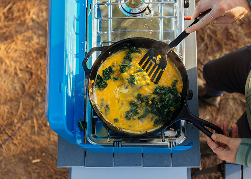 Cooking eggs on a skillet while camping.