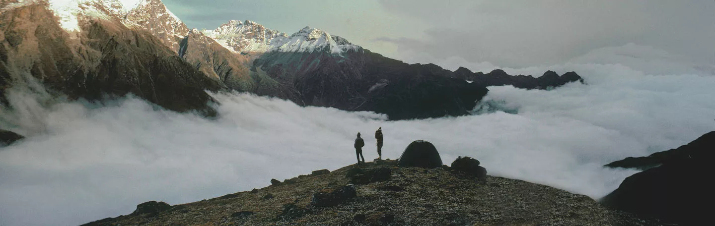 Hikers and Eureka tent on a mountain top.